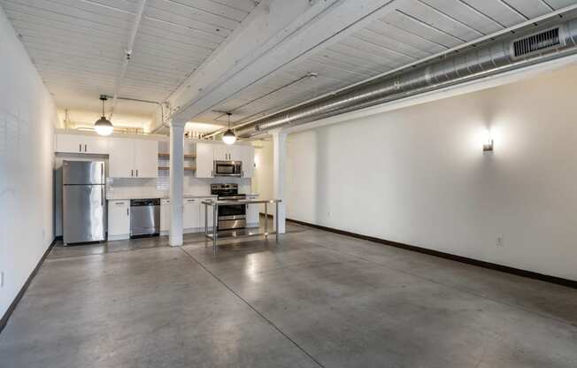 an empty room with a kitchen and a table in the middle at Highland Mill Lofts, Charlotte, North Carolina