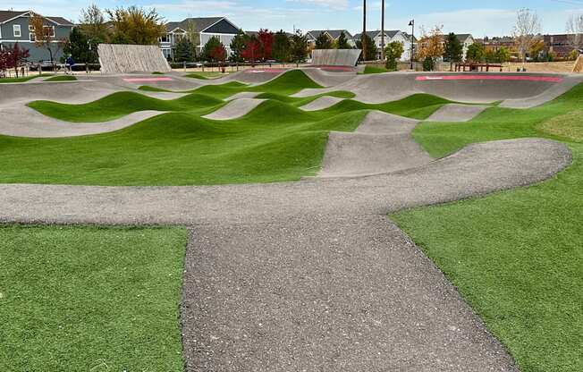 A skate park with a concrete path and green grass.