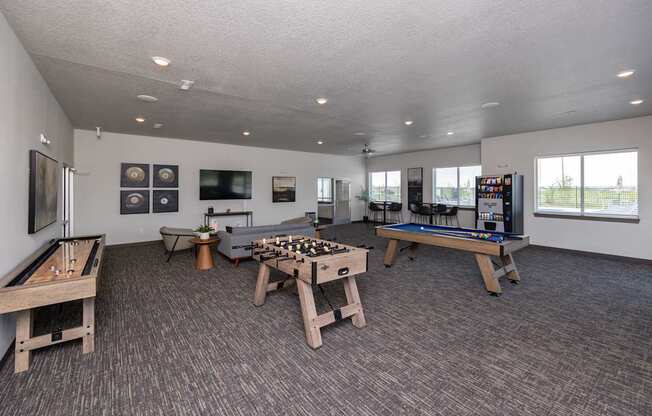 A room with a pool table, air hockey table, foosball table, and a shuffleboard table.