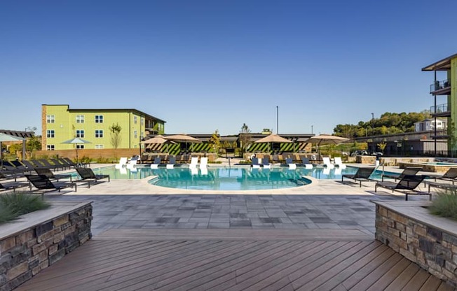 A pool area with a wooden deck and a building in the background.