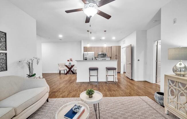 an open living room with a kitchen and a ceiling fan