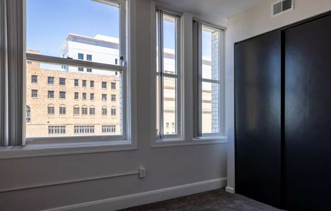 room with three windows and a door and a view of a building