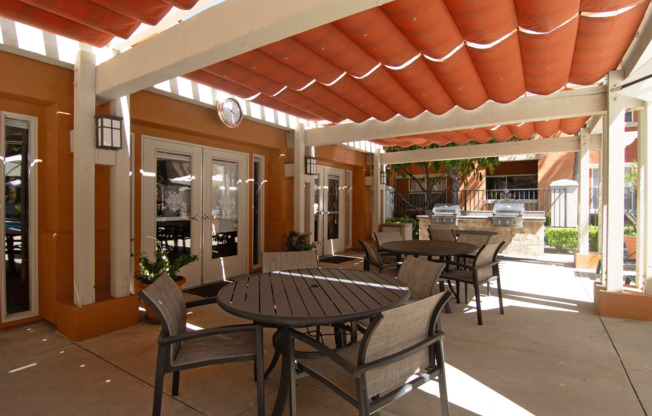 A patio with a table and chairs under a roof.