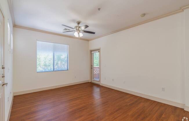 A room with a ceiling fan and wooden flooring.