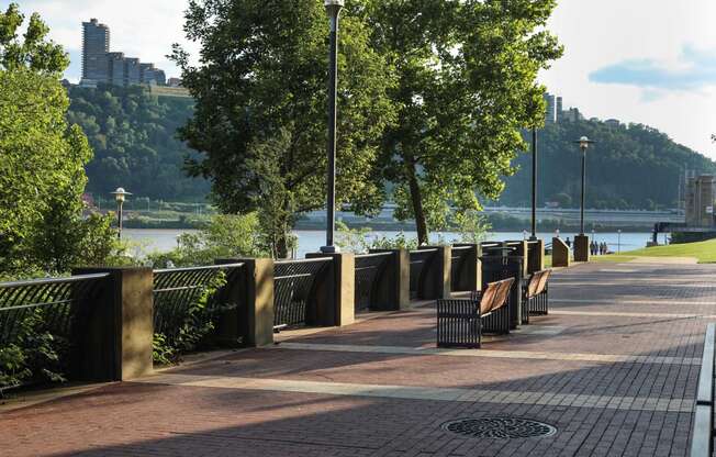 a row of benches on a sidewalk next to a river