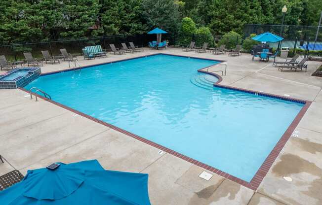 a swimming pool with blue umbrellas and chairs around it