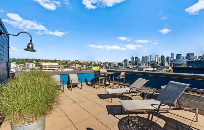 a roof deck with lounge chairs and a table with a view of the city at Dexter Lake Union, Seattle, Washington