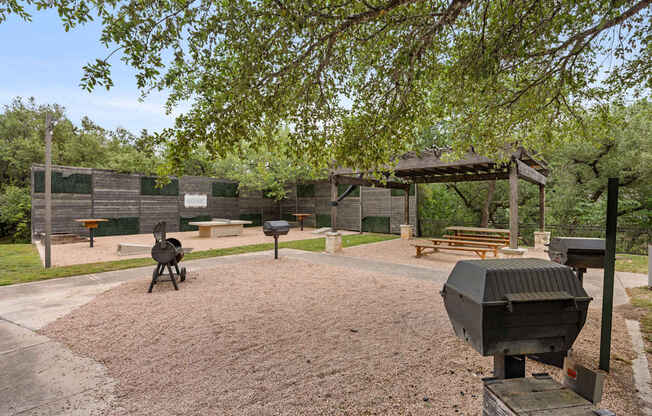 A BBQ grill is in the middle of a gravel area.