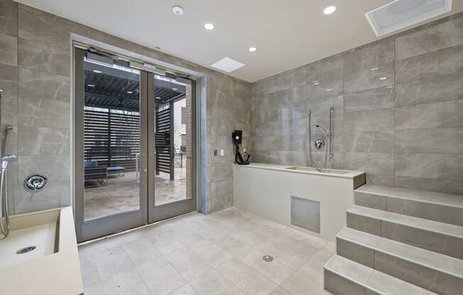 a bathroom with grey tiles and a glass door leading to a patio