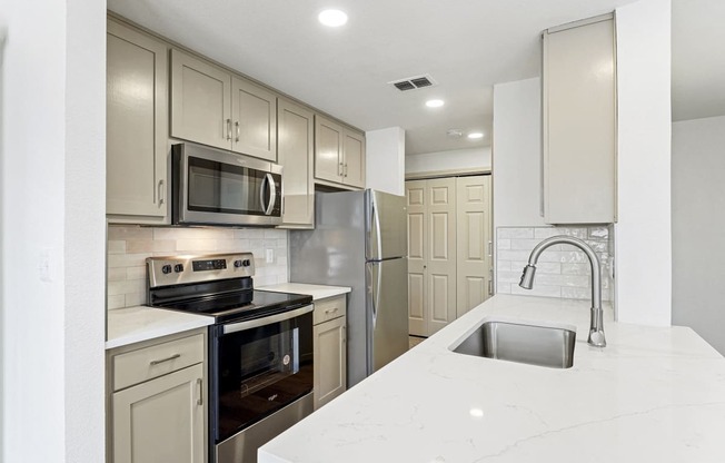 a white kitchen with stainless steel appliances and white counter tops