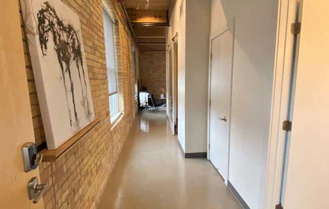 A hallway with a brick wall and a black and white patterned rug.