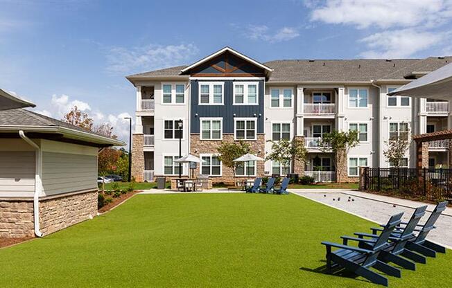 an outdoor lawn with chairs and a pool in front of an apartment building at Promenade at Newnan Crossing, Newnan, 30265