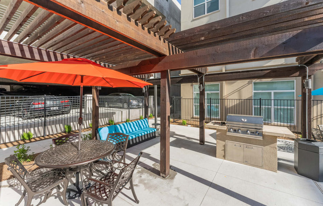 a patio with a table and chairs and a grill at Residences at 3000 Bardin Road, Grand Prairie, TX