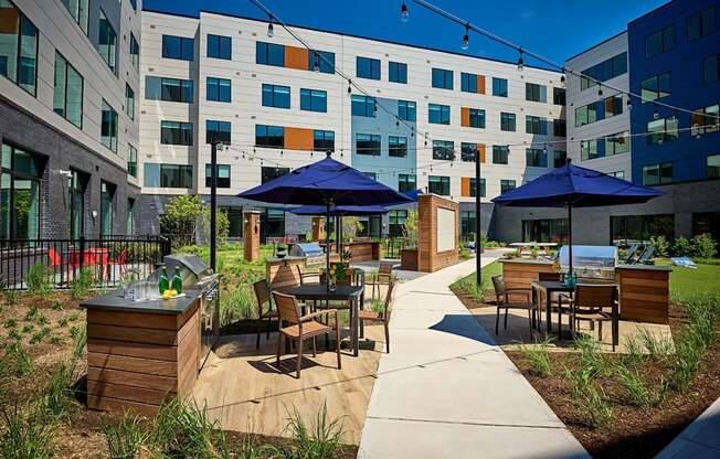 an outdoor patio with tables and umbrellas in front of an apartment building at Dey & Bergen, New Jersey, 07029