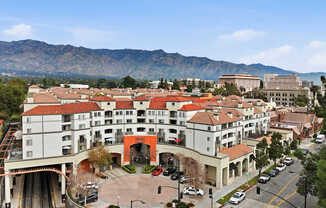 A large white building with a red roof is surrounded by mountains.