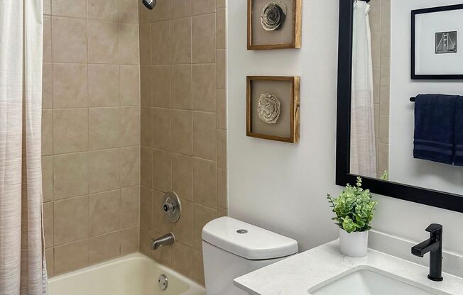 a bathroom with a white toilet next to a bathtub with a shower curtain and a sink