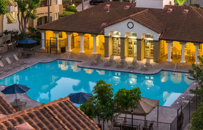 A pool surrounded by a building with a red tile roof.