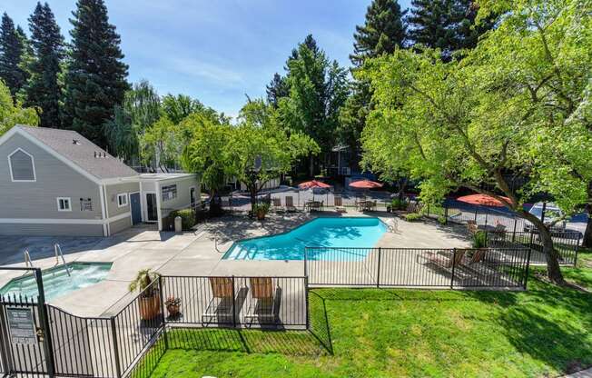 Upper View of Pool Area with Grass, Gates and Orange Patio Umbrellas 