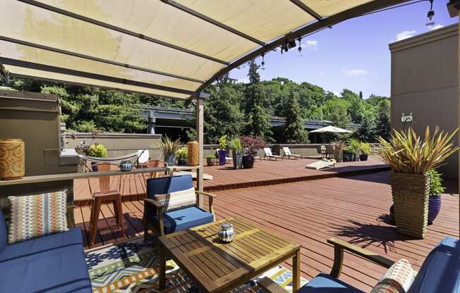 Shaded Wooden Deck Area with blue chairs and a wooden table for Relaxing at Illumina Apartment Homes, WA 98102