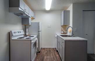 The Willows Apartments kitchen with white appliances and white cabinets and a white refrigerator and stove and sink