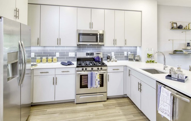 a modern kitchen with white cabinets and stainless steel appliances at The Enclave, Jersey City, NJ