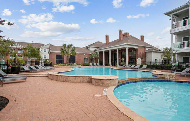 a large swimming pool with a house in the background at Volare at the Woodlands, The Woodlands, TX, 77384