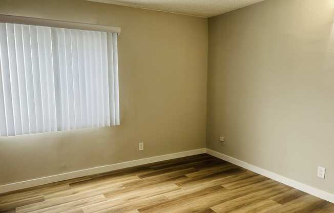 an empty room with a window and wooden floors