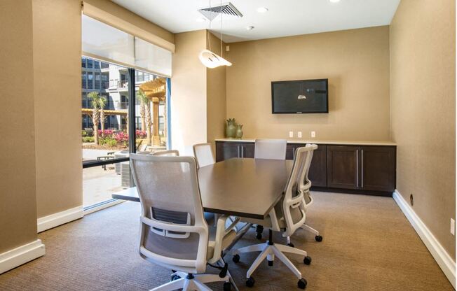 Business center with conference table with chairs and TV & printer.