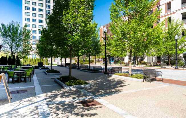A park with benches and trees in front of a building.