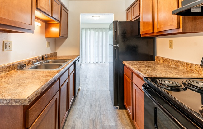 a kitchen with wood cabinets and granite counter tops and a black refrigerator