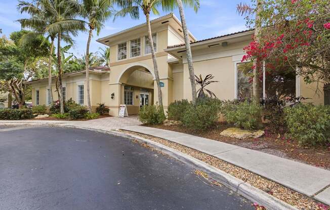 A building with a driveway and palm trees in front.