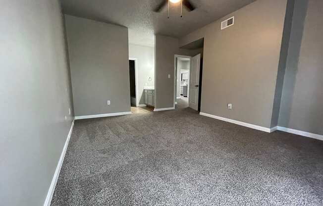 A room with a ceiling fan and carpeted floor.