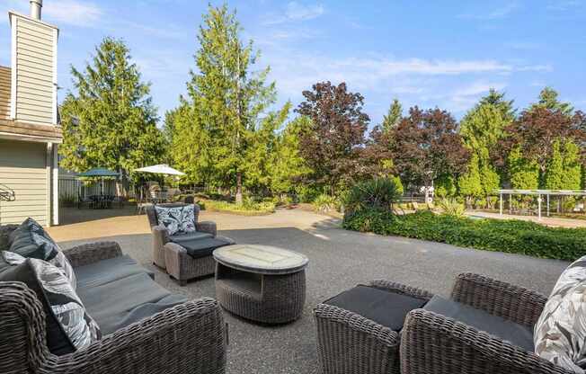 A pool deck with a wicker sofa and table set at Clackamas Trails Apartments, Oregon, 97222