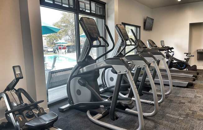 a row of treadmills and elliptical trainers in a gym