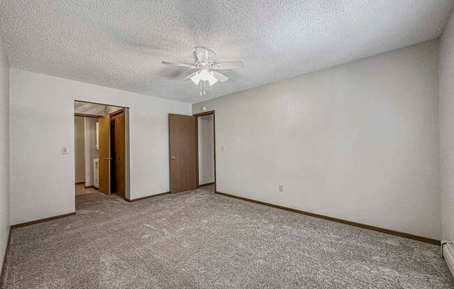 an empty living room with white walls and a ceiling fan at Creekstone Falls, Sioux Falls, 57106