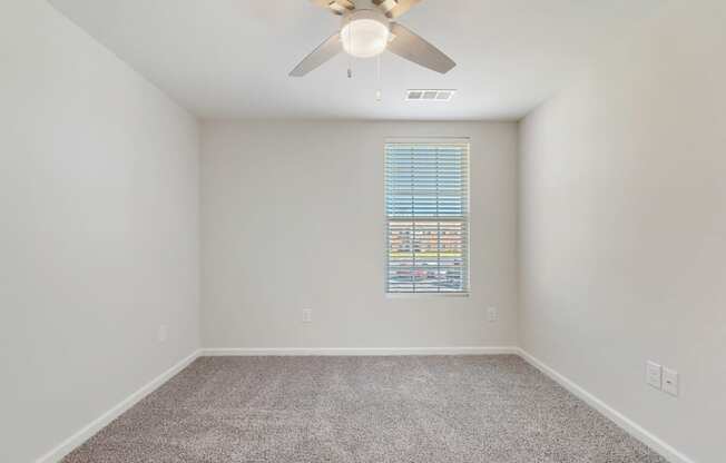 an empty room with a ceiling fan and a window