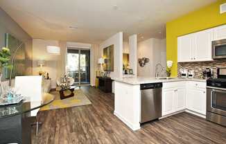A modern kitchen with white cabinets and a wooden floor at The Kitt at Warner Center Apartments, Woodland Hills