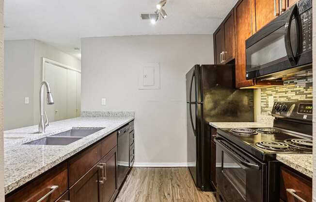 A kitchen with black appliances and wooden cabinets.