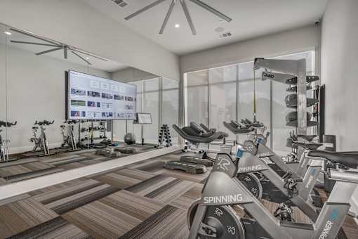 A gym with spinning bikes and a large screen on the wall.