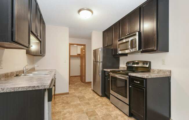 Anoka, MN Dellwood Estates Apartments. a kitchen with black cabinets and stainless steel appliances