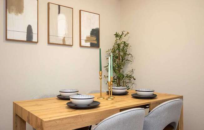 A dining table with chairs, bowls, and a vase with a plant.