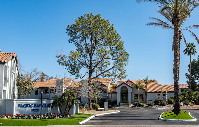 Ahwatukee, AZ, Apartments for Rent - Pacific Bay Club - Property Exterior with White Walls, Terracotta Roofing, Driveway, and Palm Trees.