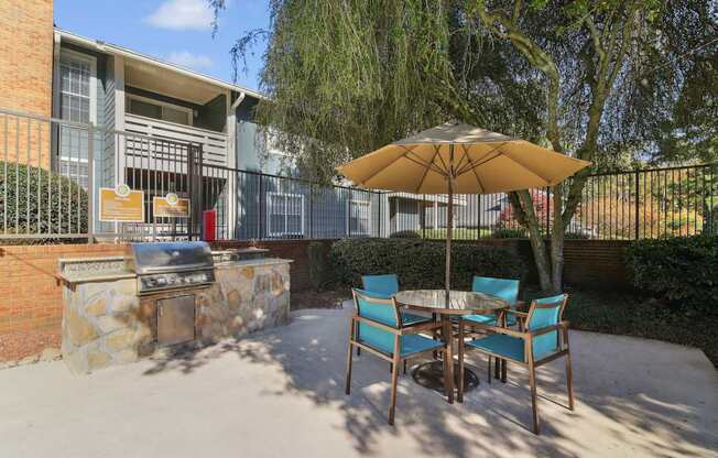 A patio with a table, chairs and an umbrella.