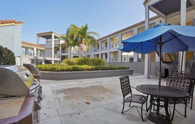 A patio with a table and chairs and a grill.