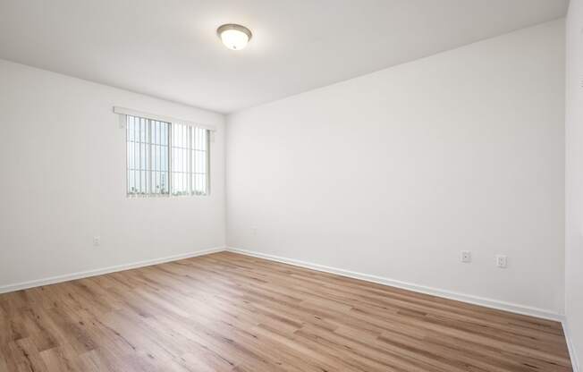 an empty living room with white walls and wood floors