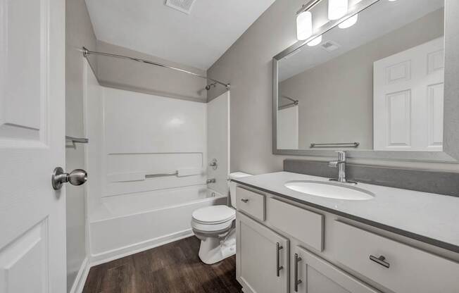 A white bathroom with a toilet, sink, and mirror.