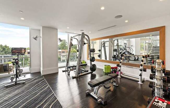 A gym with a mirror, weights, and cardio equipment.