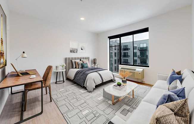 A modern bedroom with a large bed, a desk, and a couch.