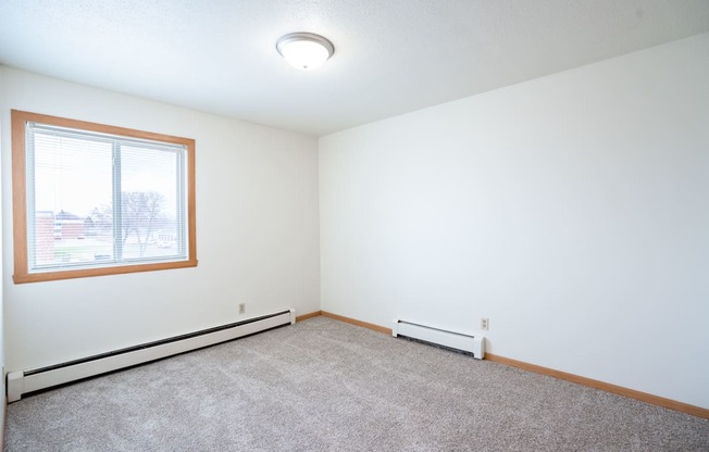 A room with a window and carpeted floor. West Fargo, ND Saddlebrook Apartments