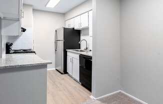 an empty kitchen with white appliances and a black refrigerator